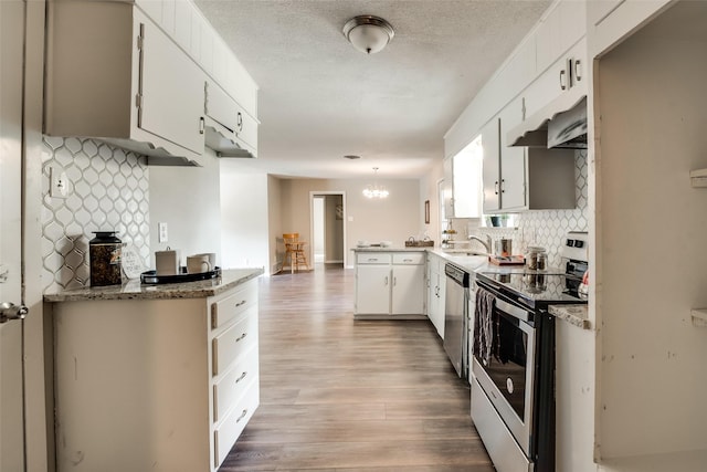 kitchen featuring pendant lighting, white cabinetry, backsplash, stainless steel appliances, and light wood-type flooring