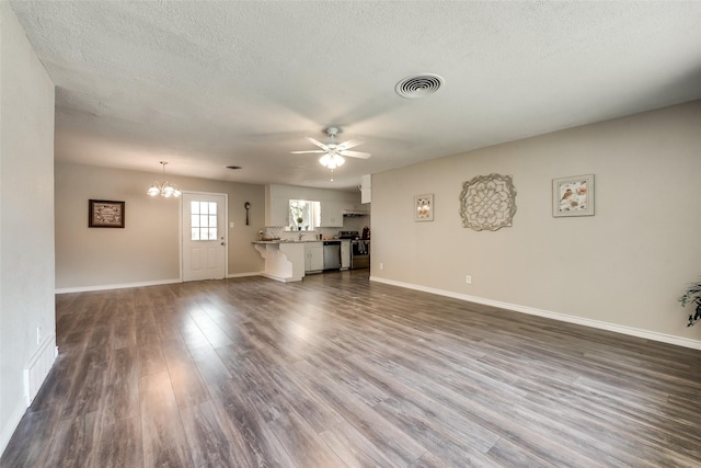 unfurnished living room with dark hardwood / wood-style floors, ceiling fan with notable chandelier, and a textured ceiling