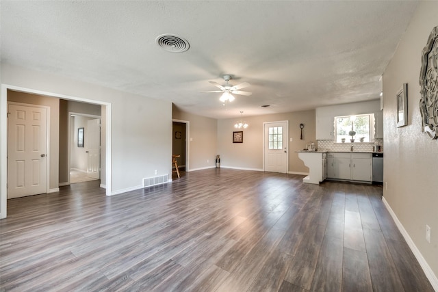 unfurnished living room featuring wood-type flooring, ceiling fan with notable chandelier, and a textured ceiling