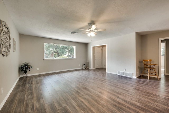 unfurnished room featuring ceiling fan, dark wood-type flooring, a wealth of natural light, and a textured ceiling