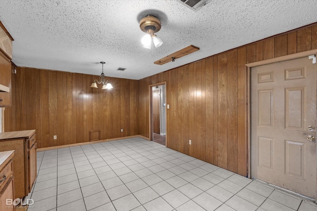 interior space with wooden walls, a textured ceiling, and an inviting chandelier