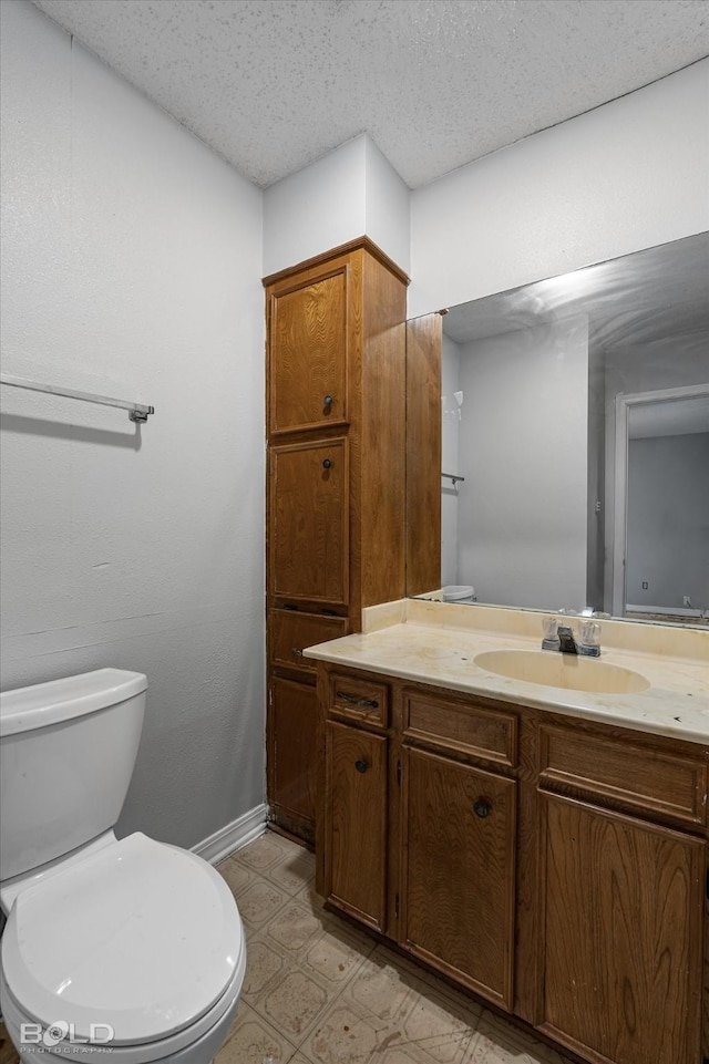 bathroom featuring vanity, a textured ceiling, and toilet