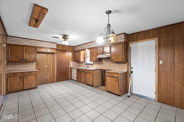 kitchen with white dishwasher, sink, decorative light fixtures, and wood walls