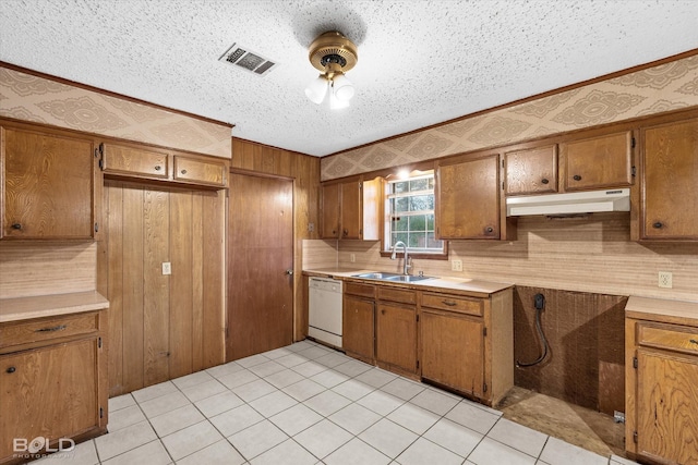 kitchen featuring dishwasher, sink, backsplash, light tile patterned floors, and a textured ceiling