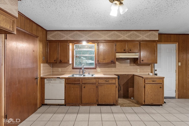 kitchen featuring sink, crown molding, backsplash, white dishwasher, and wood walls