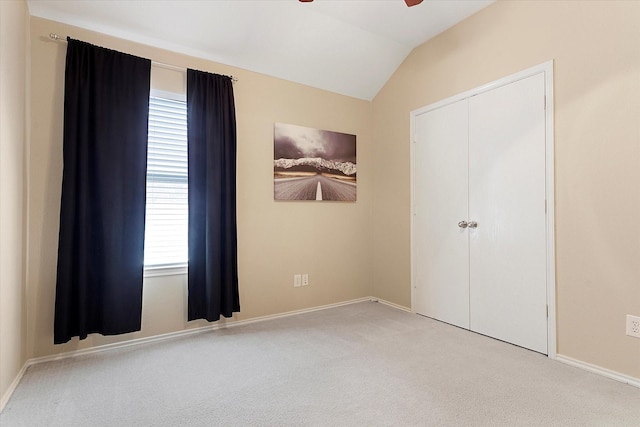 unfurnished bedroom featuring lofted ceiling, light colored carpet, ceiling fan, and a closet