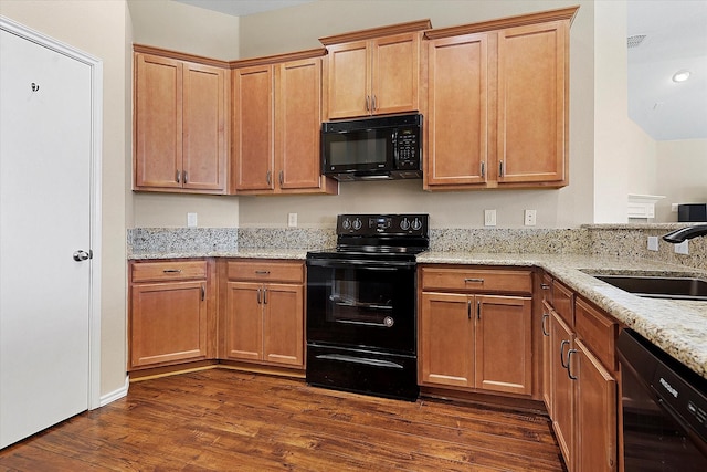 kitchen featuring light stone counters, sink, dark hardwood / wood-style flooring, and black appliances