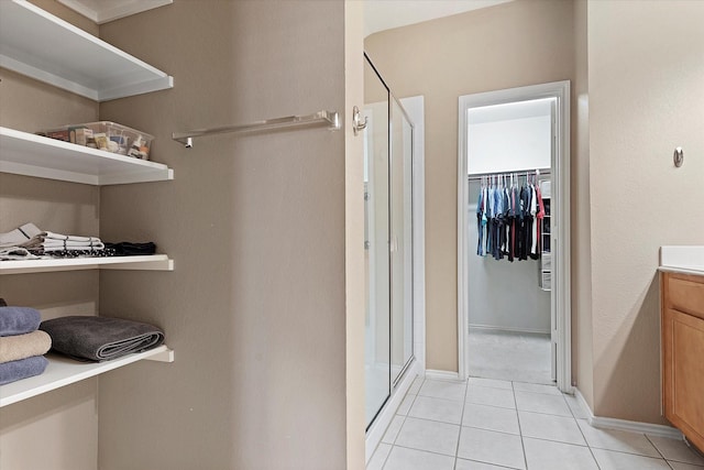 bathroom with tile patterned floors, a shower with shower door, and vanity