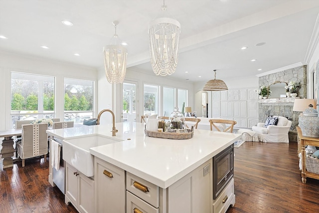 kitchen featuring pendant lighting, black microwave, sink, a center island with sink, and an inviting chandelier