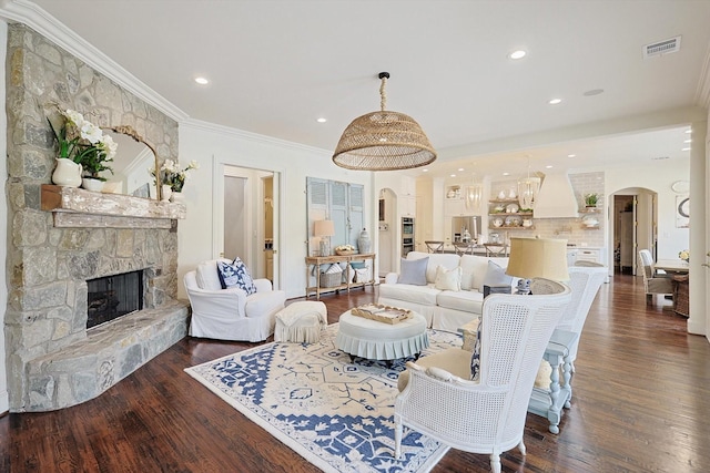 living room with a stone fireplace, ornamental molding, and dark hardwood / wood-style floors