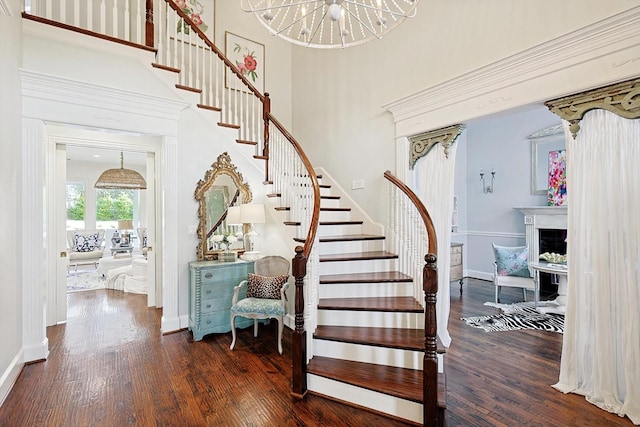 stairway featuring hardwood / wood-style flooring, a towering ceiling, and a notable chandelier