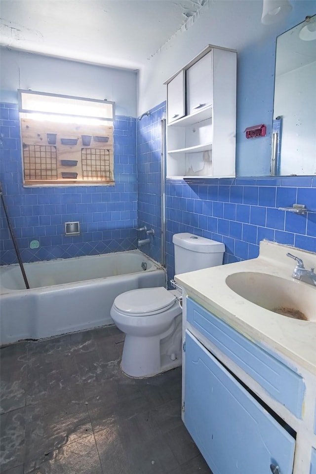 full bathroom featuring tiled shower / bath, vanity, toilet, and tile walls