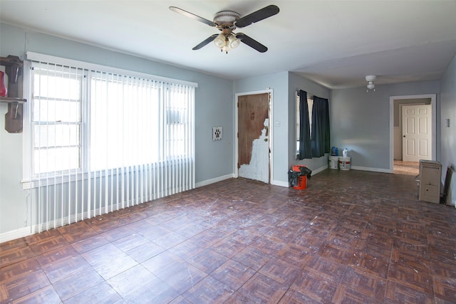 unfurnished room with dark parquet flooring and ceiling fan