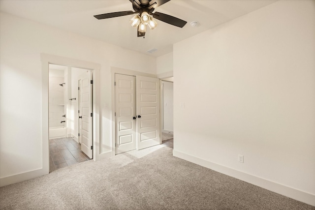 interior space featuring light carpet, connected bathroom, a closet, and ceiling fan