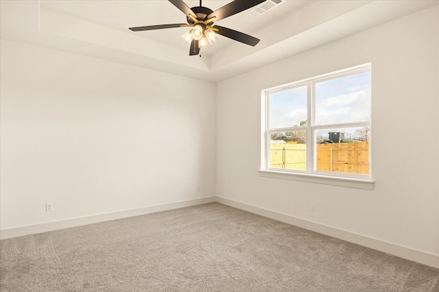 carpeted spare room with ceiling fan and a raised ceiling