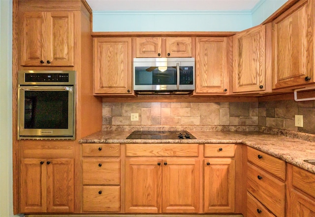 kitchen with tasteful backsplash, light stone counters, crown molding, and appliances with stainless steel finishes