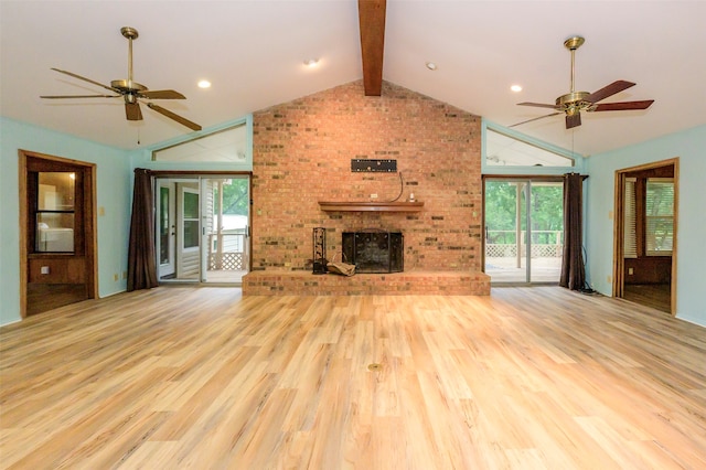 unfurnished living room featuring plenty of natural light, lofted ceiling with beams, a brick fireplace, and light wood-type flooring