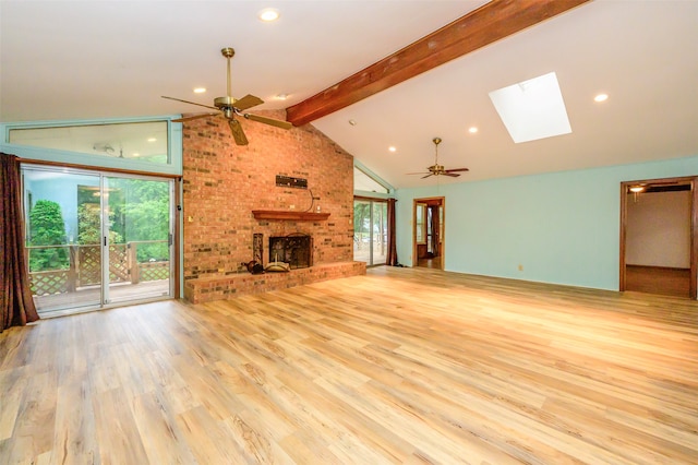 unfurnished living room with a brick fireplace, light hardwood / wood-style floors, vaulted ceiling with skylight, and ceiling fan