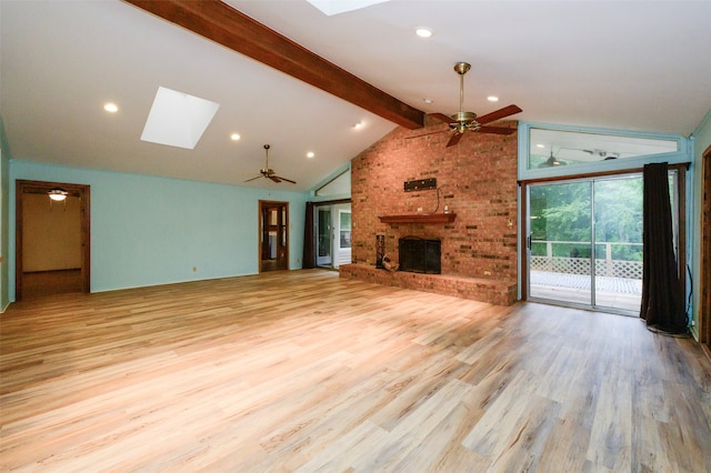 unfurnished living room featuring a fireplace, lofted ceiling with skylight, light hardwood / wood-style floors, and ceiling fan