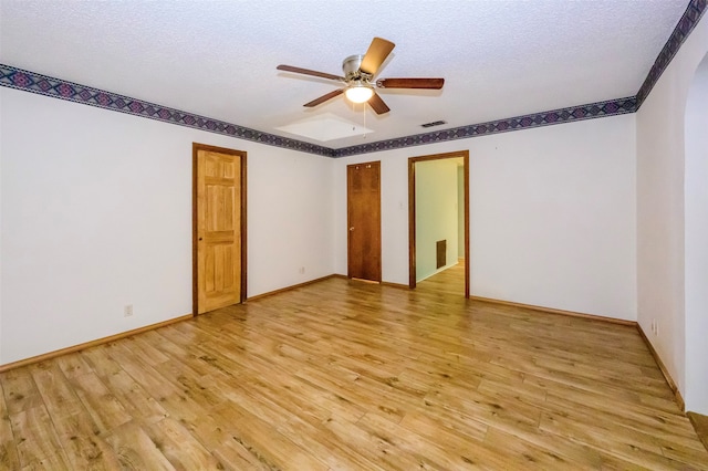 spare room featuring ceiling fan, light hardwood / wood-style flooring, and a textured ceiling