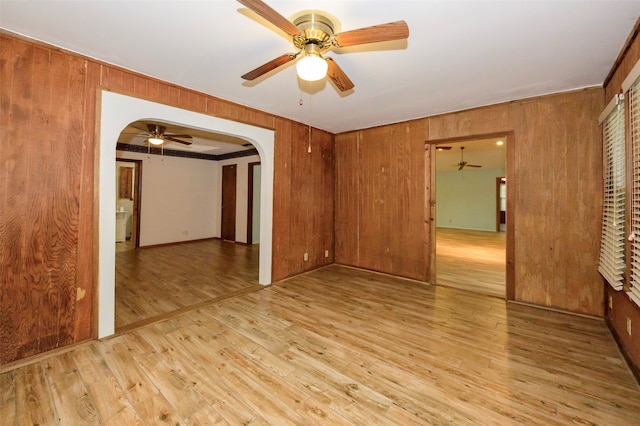 spare room with light hardwood / wood-style flooring and wood walls