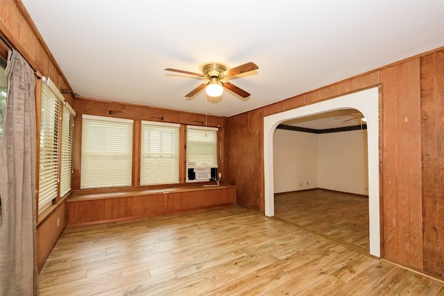 interior space featuring cooling unit, ceiling fan, wooden walls, and light hardwood / wood-style floors