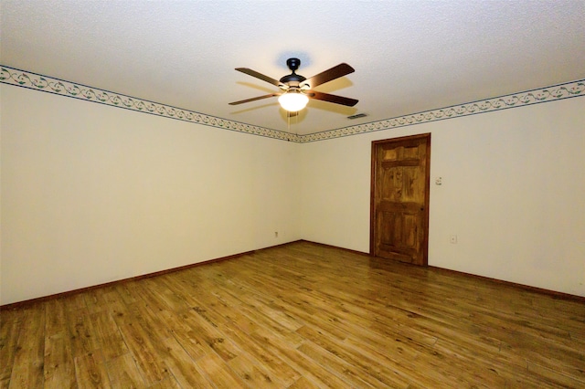 empty room with a textured ceiling, wood-type flooring, and ceiling fan