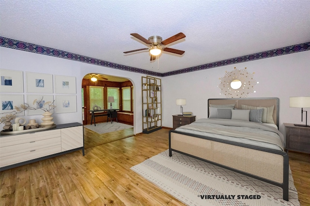 bedroom with ceiling fan, hardwood / wood-style floors, and a textured ceiling