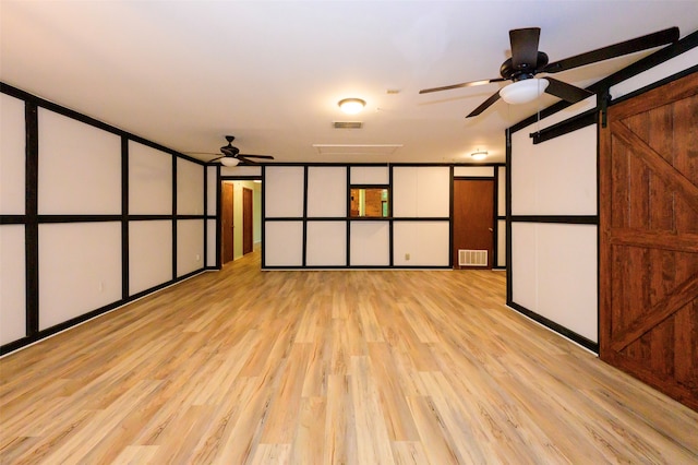 cinema with ceiling fan, a barn door, and light hardwood / wood-style flooring