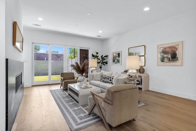 living room featuring a high end fireplace and light wood-type flooring