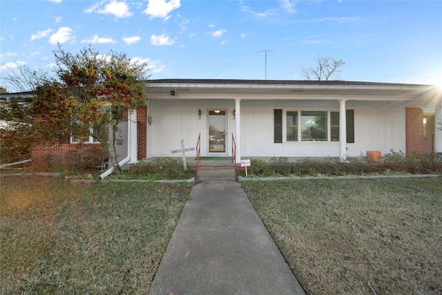 ranch-style home featuring covered porch and a front lawn