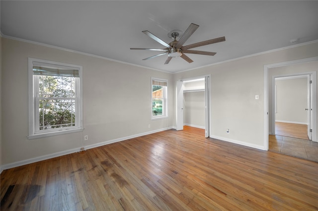 unfurnished bedroom with ceiling fan, ornamental molding, a closet, and light wood-type flooring