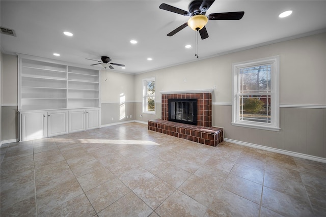 unfurnished living room with crown molding, ceiling fan, a tile fireplace, and built in features