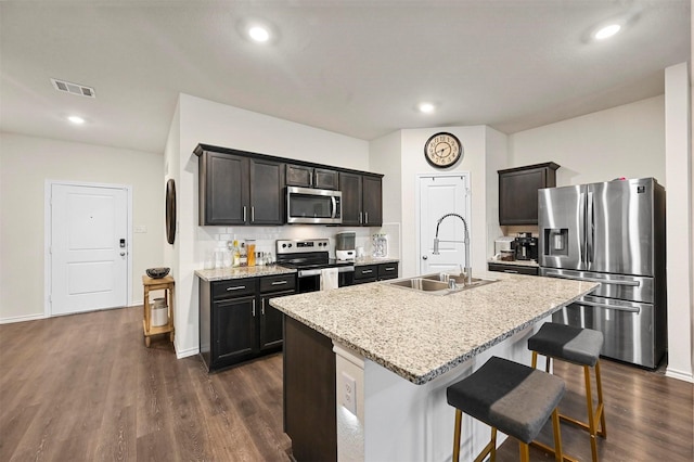 kitchen featuring sink, a breakfast bar area, stainless steel appliances, dark hardwood / wood-style floors, and a center island with sink