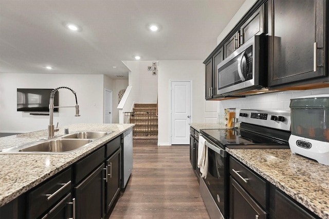 kitchen featuring sink, dark wood-type flooring, appliances with stainless steel finishes, light stone countertops, and decorative backsplash