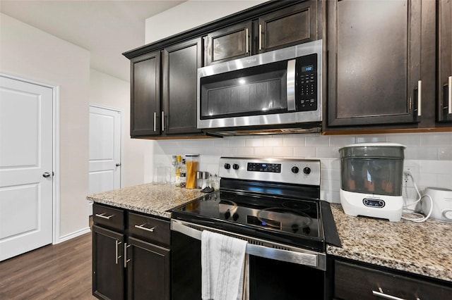 kitchen with dark brown cabinetry, light stone counters, dark hardwood / wood-style floors, stainless steel appliances, and decorative backsplash