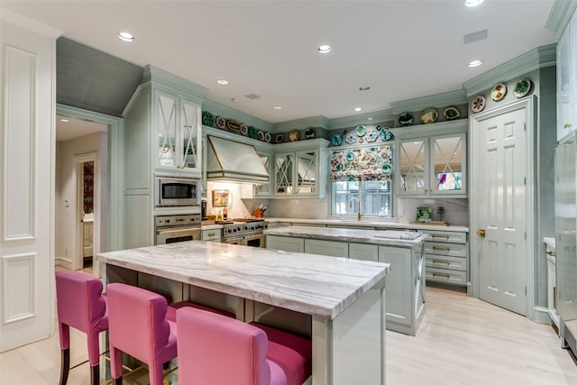 kitchen with stainless steel appliances, custom range hood, light hardwood / wood-style floors, and a kitchen island