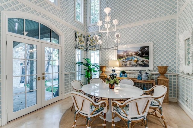 dining space with a notable chandelier, french doors, light parquet floors, and a high ceiling