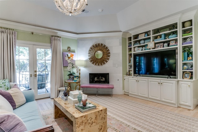 living room featuring light hardwood / wood-style flooring, a fireplace, french doors, and a chandelier