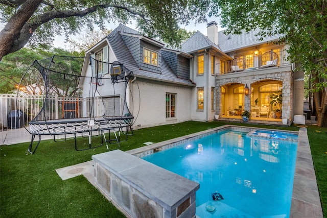 back of property featuring a balcony, a yard, and a trampoline