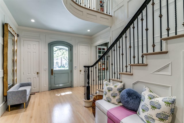 foyer entrance featuring crown molding and light hardwood / wood-style flooring