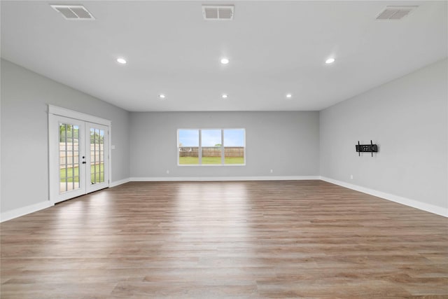 empty room with plenty of natural light, light hardwood / wood-style flooring, and french doors