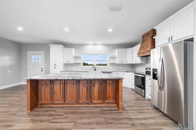 kitchen featuring appliances with stainless steel finishes, a center island, light stone countertops, and white cabinets