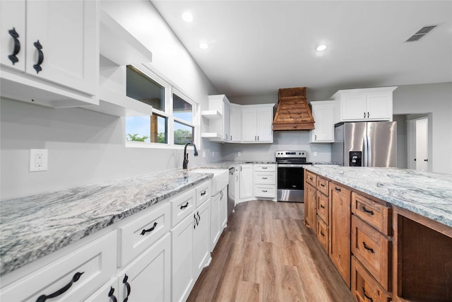 kitchen featuring premium range hood, white cabinets, and appliances with stainless steel finishes