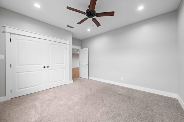 unfurnished bedroom with ceiling fan, light colored carpet, and a closet