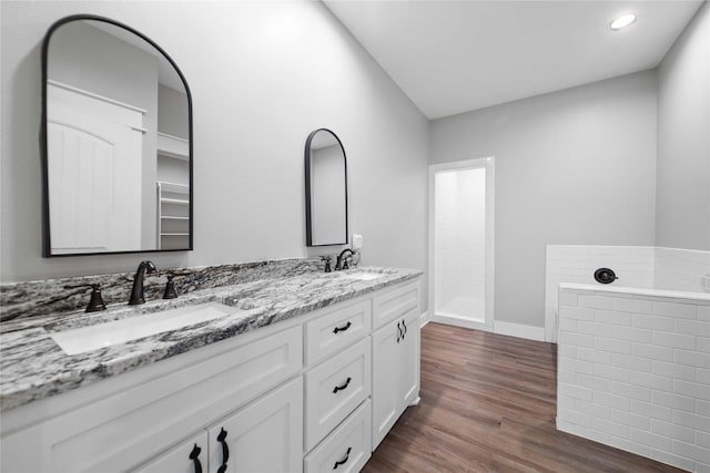 bathroom featuring vanity, hardwood / wood-style floors, and a relaxing tiled tub