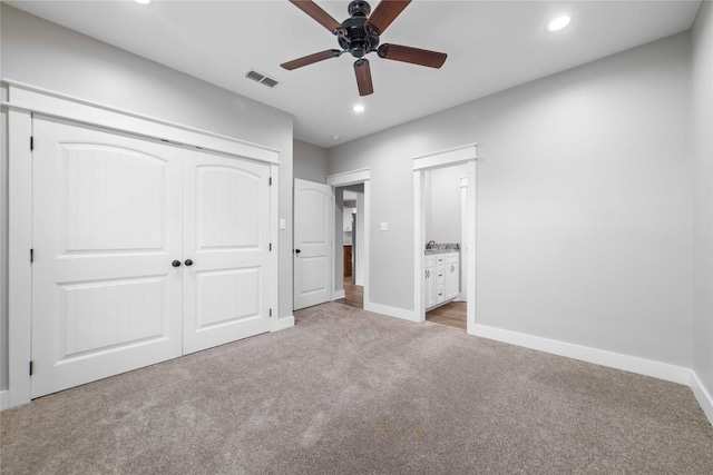 unfurnished bedroom with connected bathroom, light colored carpet, ceiling fan, and a closet