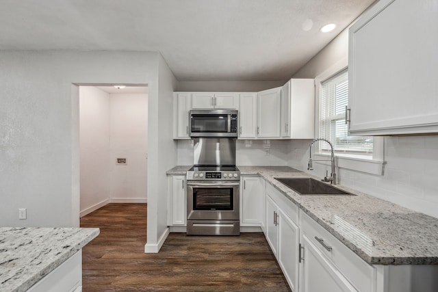 kitchen featuring sink, appliances with stainless steel finishes, white cabinetry, light stone counters, and dark hardwood / wood-style flooring