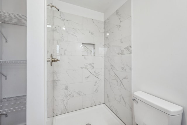 bathroom featuring a tile shower and toilet