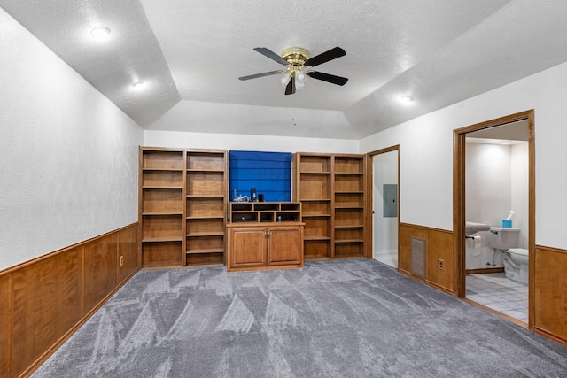 unfurnished living room with vaulted ceiling, carpet flooring, a textured ceiling, and wood walls